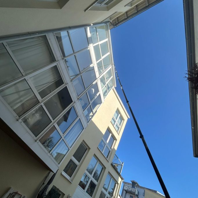 Blick auf ein Gebäude mit großen Fenstern und einem Kran, der in den Himmel ragt.